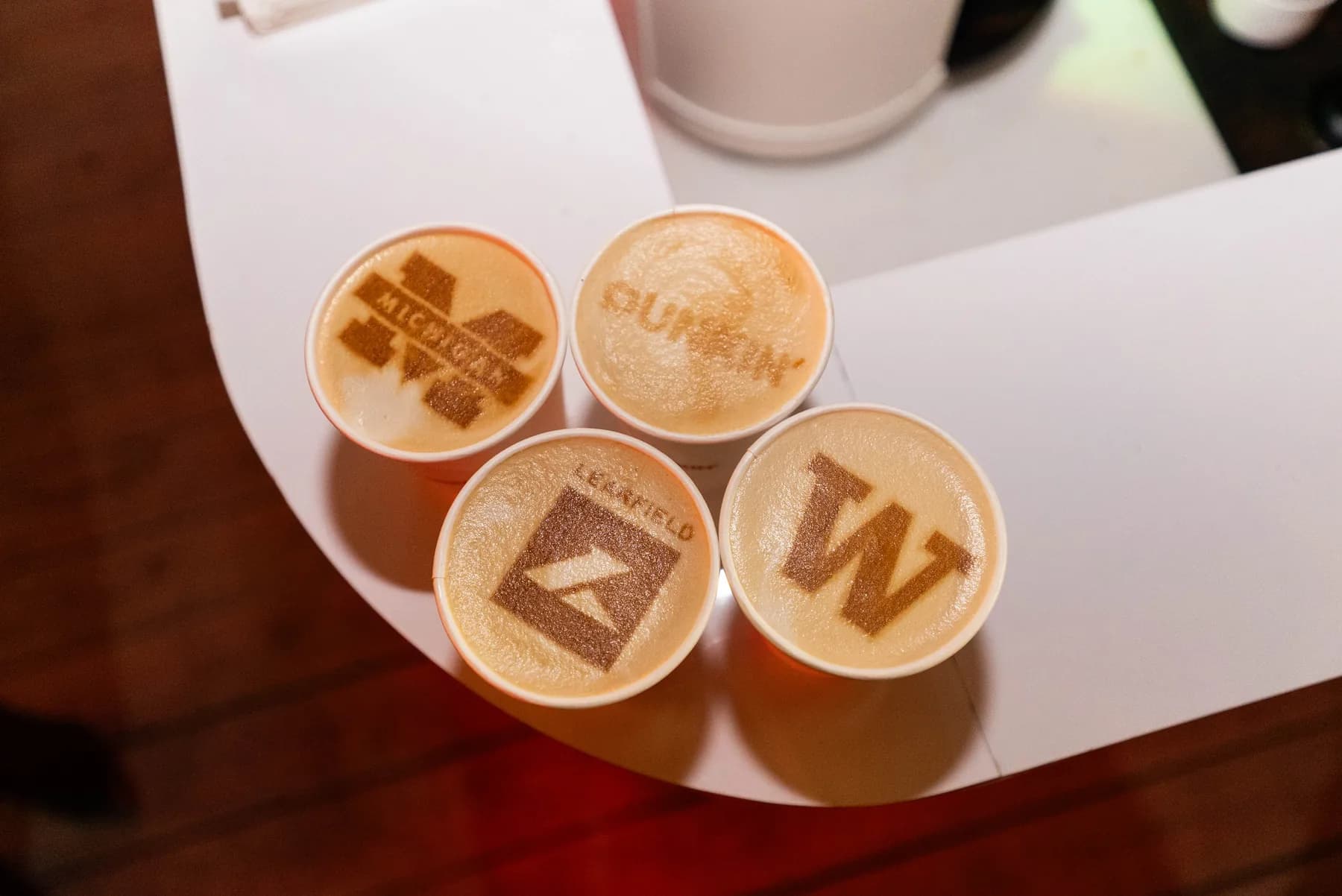 Four lattes with corporate logos printed in the foam at a Houston brand activation