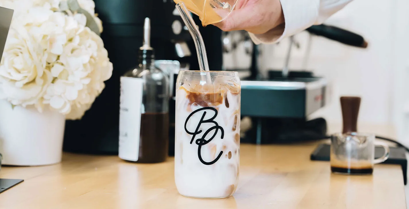 Barista pouring milk into a branded Brightside cup at a Houston wedding coffee bar
