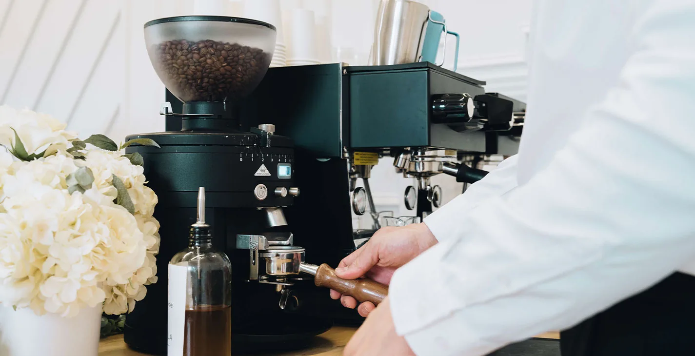 Espresso grinder and white florals styled on a Houston wedding coffee bar